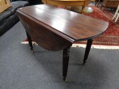 A 19th century mahogany flap sided dining table with two leaves on reeded legs.