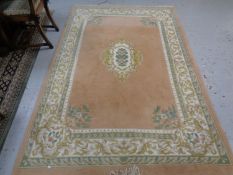 A Chinese woolen embossed fringed floral rug on peach ground,