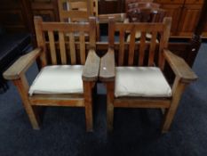 A pair of Barlow Tyrie heavy teak garden armchairs with cushions.