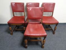 A set of four oak dining chairs upholstered in red buttoned leather.