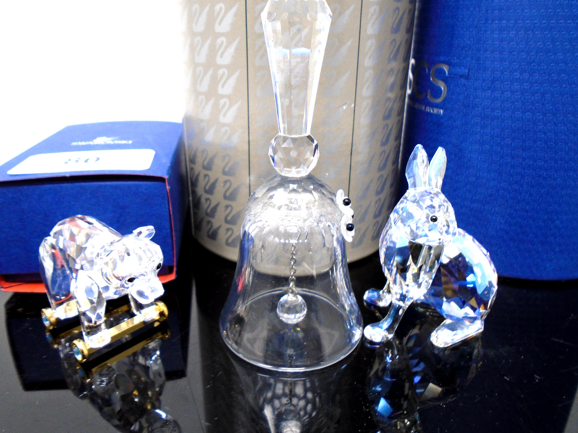 Three Swarovski crystal ornaments, miniature bell, hare and bear cub on wheels.