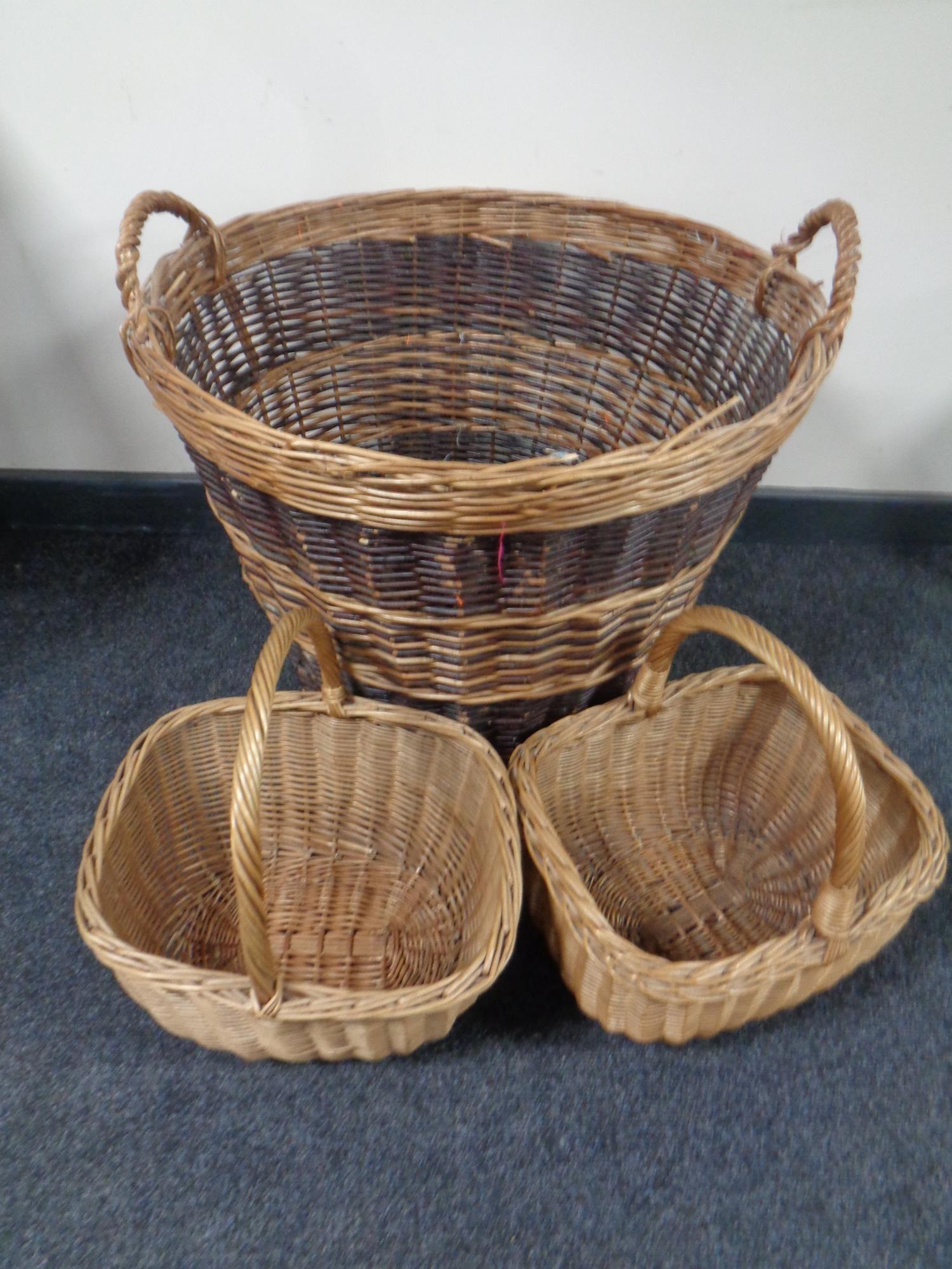 A large wicker twin-handled log basket together with two further wicker shopping baskets.