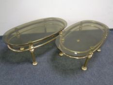 A pair of oval brass smoked glass top tables.