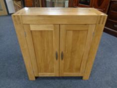 An Oak Furniture Land double door cabinet fitted with internal shelves.