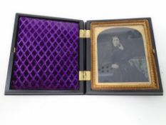 A 19th century carved ebony case containing a Daguerreotype photograph of a lady in a gilt frame.