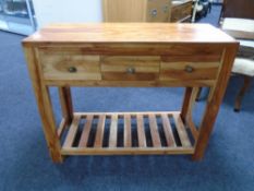 A sheesham wood three drawer console table with undershelf.