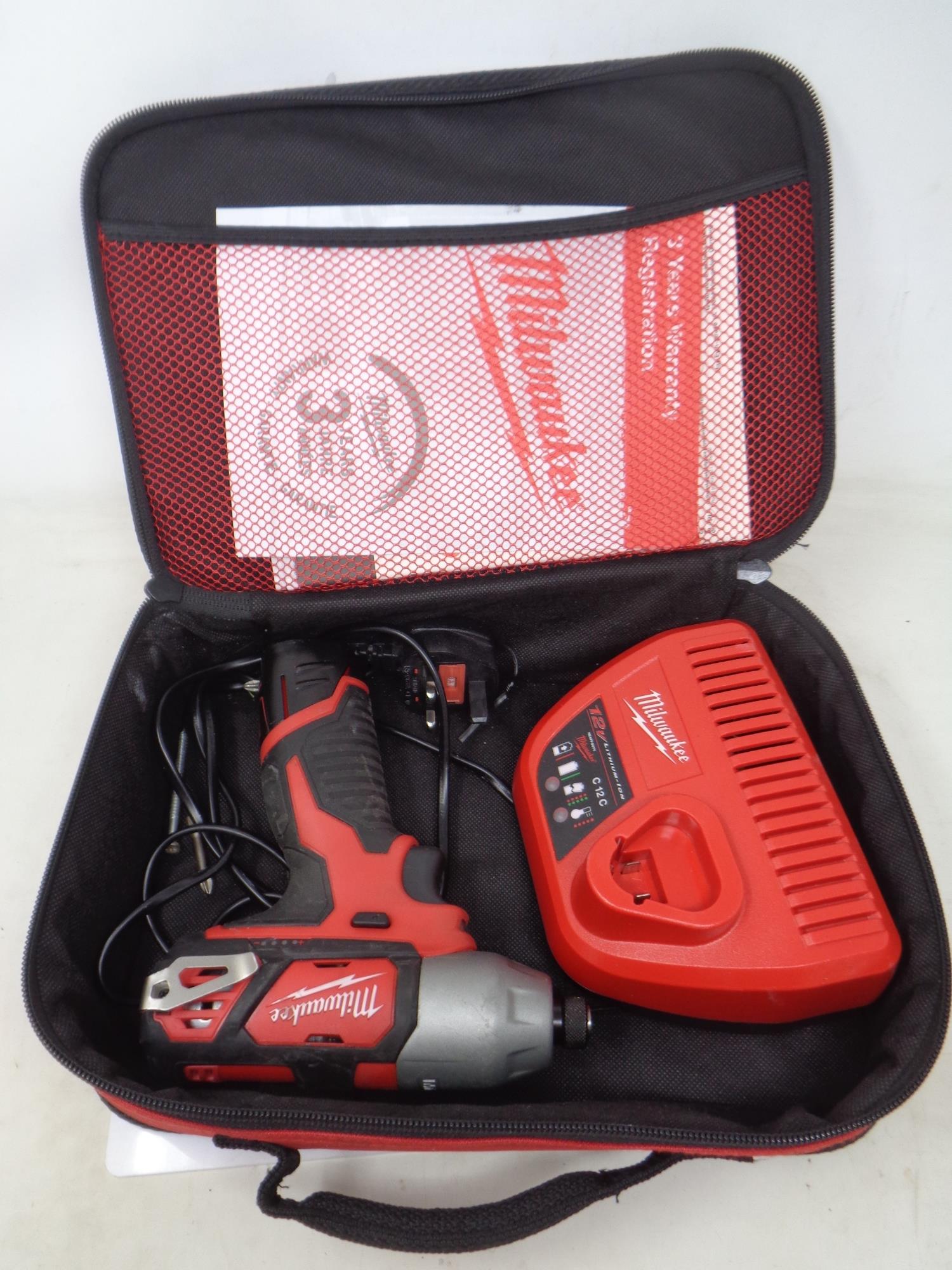 A Milwaukee Impact drill with battery and charger in carry case.