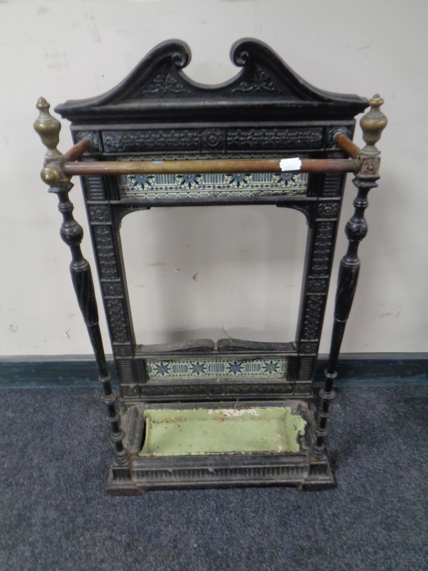 A Victorian cast iron and brass tiled back stick stand with tray.