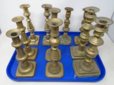 A tray containing five pairs of 19th century brass candlesticks.