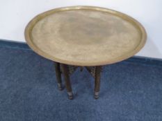 An Egyptian style engraved brass top table on folding base.