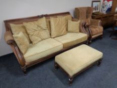 A Victorian style carved wooden frame settee with matching footstool upholstered in a two tone
