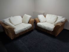A pair of oversized wicker conservatory armchairs with cushions.