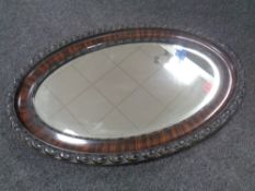 An Edwardian bevel edged mirror in oval mahogany frame.