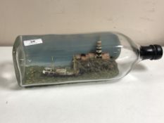 A large glass bottle containing a boat and lighthouse diorama, length 35 cm.