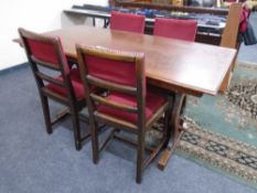 An oak refectory dining table together with a set of four chairs upholstered in red dralon.