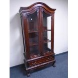 A reproduction double door arch topped display cabinet fitted a drawer on claw and ball feet