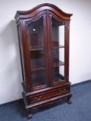 A reproduction double door arch topped display cabinet fitted a drawer on claw and ball feet