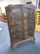 A walnut glazed double door bookcase on cabriole legs