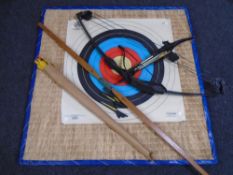An archery target together with two bows, arrows and a crossbow with bolts.