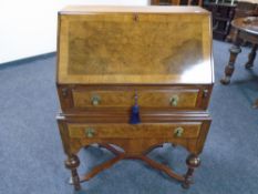 An Edwardian walnut inlaid writing bureau fitted with two drawers on raised legs.