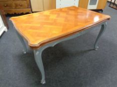A French walnut marquetry topped extending dining table on painted cabriole legs.