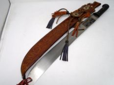 A South American machete in tooled leather sheath.