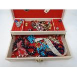 A jewellery box containing a quantity of assorted costume jewellery including beaded necklaces,