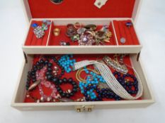 A jewellery box containing a quantity of assorted costume jewellery including beaded necklaces,