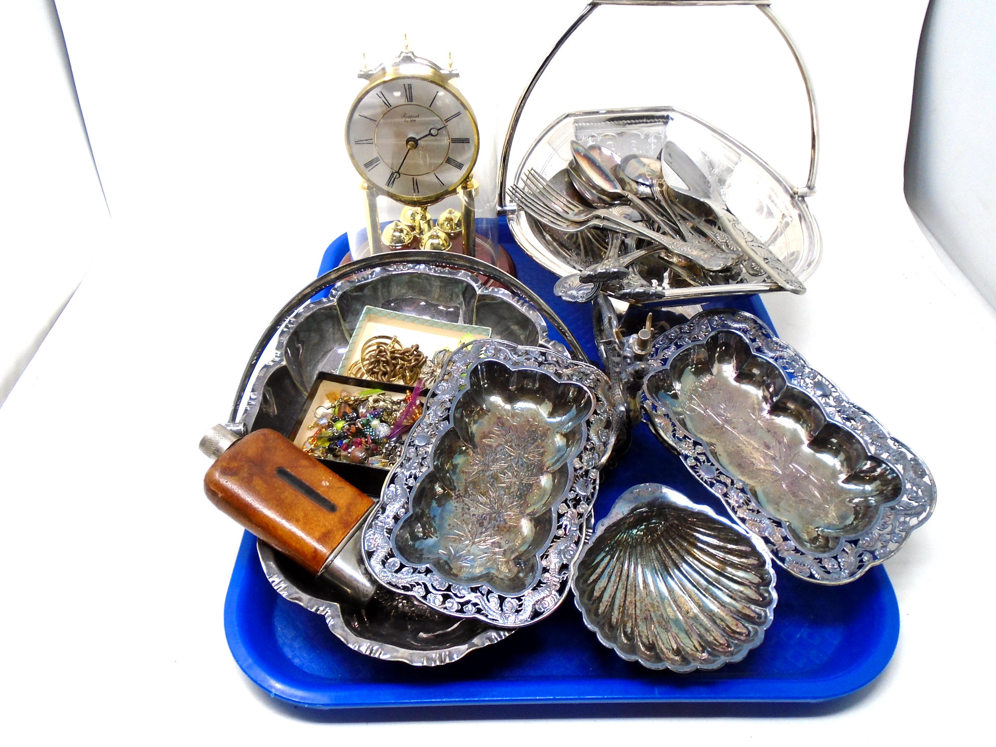 A tray containing costume jewellery, assorted plated wares, a Rapport anniversary clock under shade.