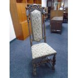 An 18th century carved oak high backed hall chair in tapestry fabric