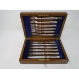 An Edwardian oak cutlery canteen containing a set of six silver plated fish knives and forks.