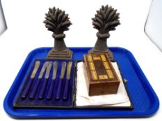 A tray of 19th century cast iron wheat sheaf door stops together with a set of cased butter knives