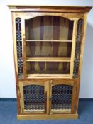 A sheesham wood bookcase fitted with double door cupboard below and wrought iron panels.