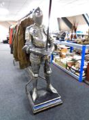 A figure of a medieval knight with spear, on plinth.