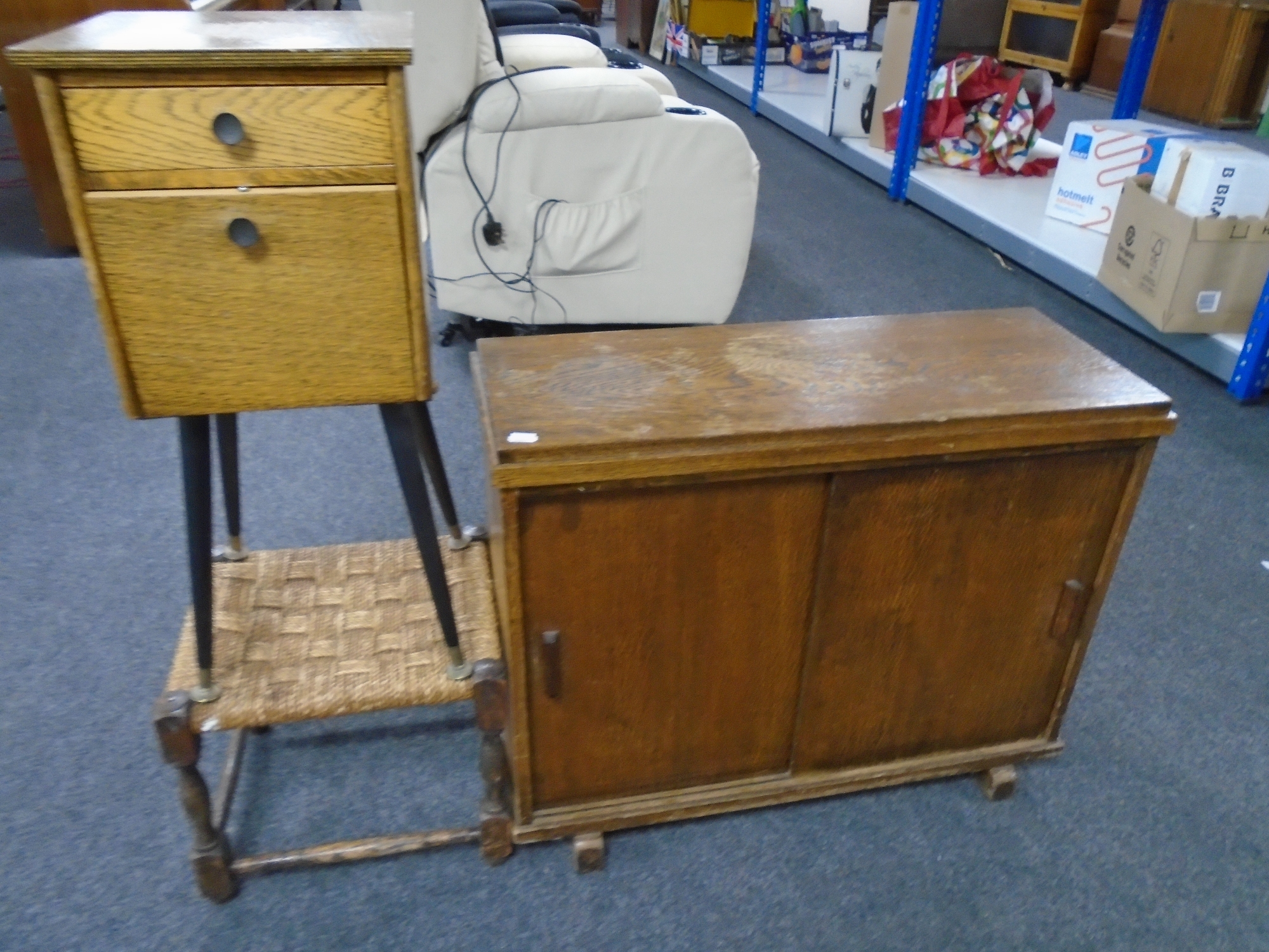 A mid century oak sliding double door cupboard together with a cabinet on raised legs and rush