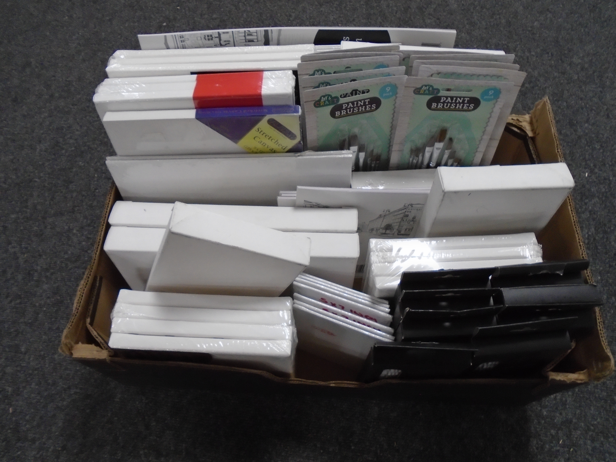 A box containing art supplies including Colvin & Co acrylic paints, canvasses, sketch pads,