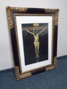 A colour print depicting the crucifixion of Christ in an ornate black and gilt frame.
