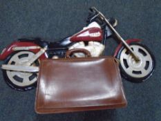 A vintage leather briefcase together with a wall art metal motorcycle.
