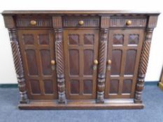 A continental stained pine triple door sideboard fitted with three drawers above with twist column