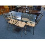 A contemporary glass topped dining table with set of six metal chairs