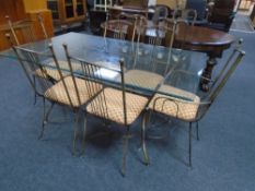 A contemporary glass topped dining table with set of six metal chairs