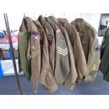 Seven 20th century British army tunics bearing badges together with three pairs of trousers (11)