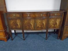 A Regency style mahogany serpentine fronted four door sideboard on raised legs.