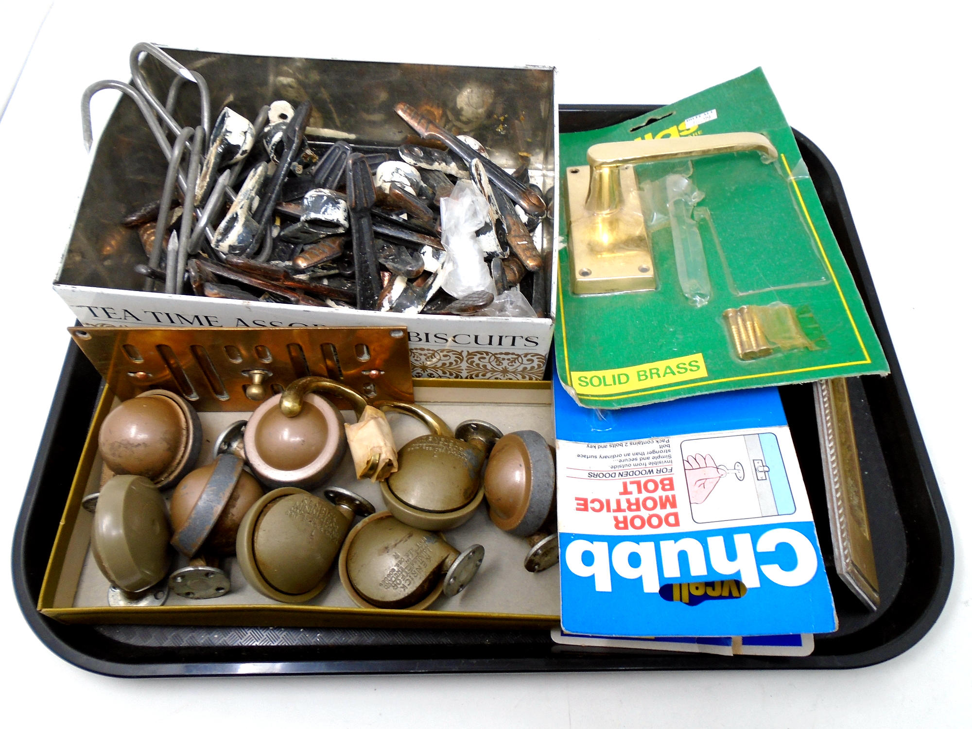 A tray containing furniture castors, door furniture, brass letterbox etc.