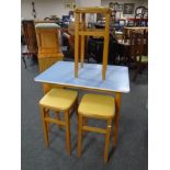 A mid-20th century melamine topped kitchen table together with a set of three stools.