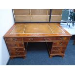 A yew wood nine drawer twin pedestal writing desk with a brown tooled leather inset panel,