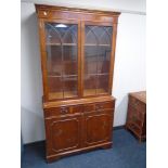 A yew wood glazed double door bookcase fitted with cupboards and drawers beneath,