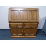 An Ercol Grasmere writing bureau fitted with drawers and cupboards beneath.