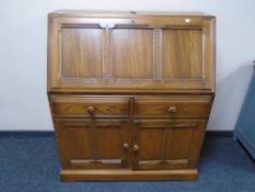 An Ercol Grasmere writing bureau fitted with drawers and cupboards beneath.