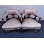 A pair of Edwardian mahogany low tub chairs upholstered in striped fabric.